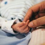 person holding baby's index finger